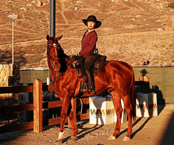 Dawn Champion posing on her brown horse wearing Scoot Boots in the desert
